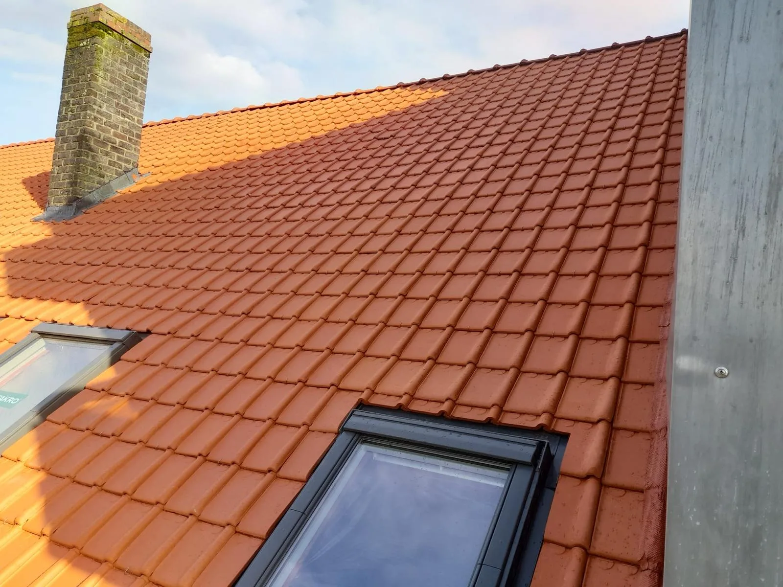 Rood pannendak met schoorsteen en dakraam