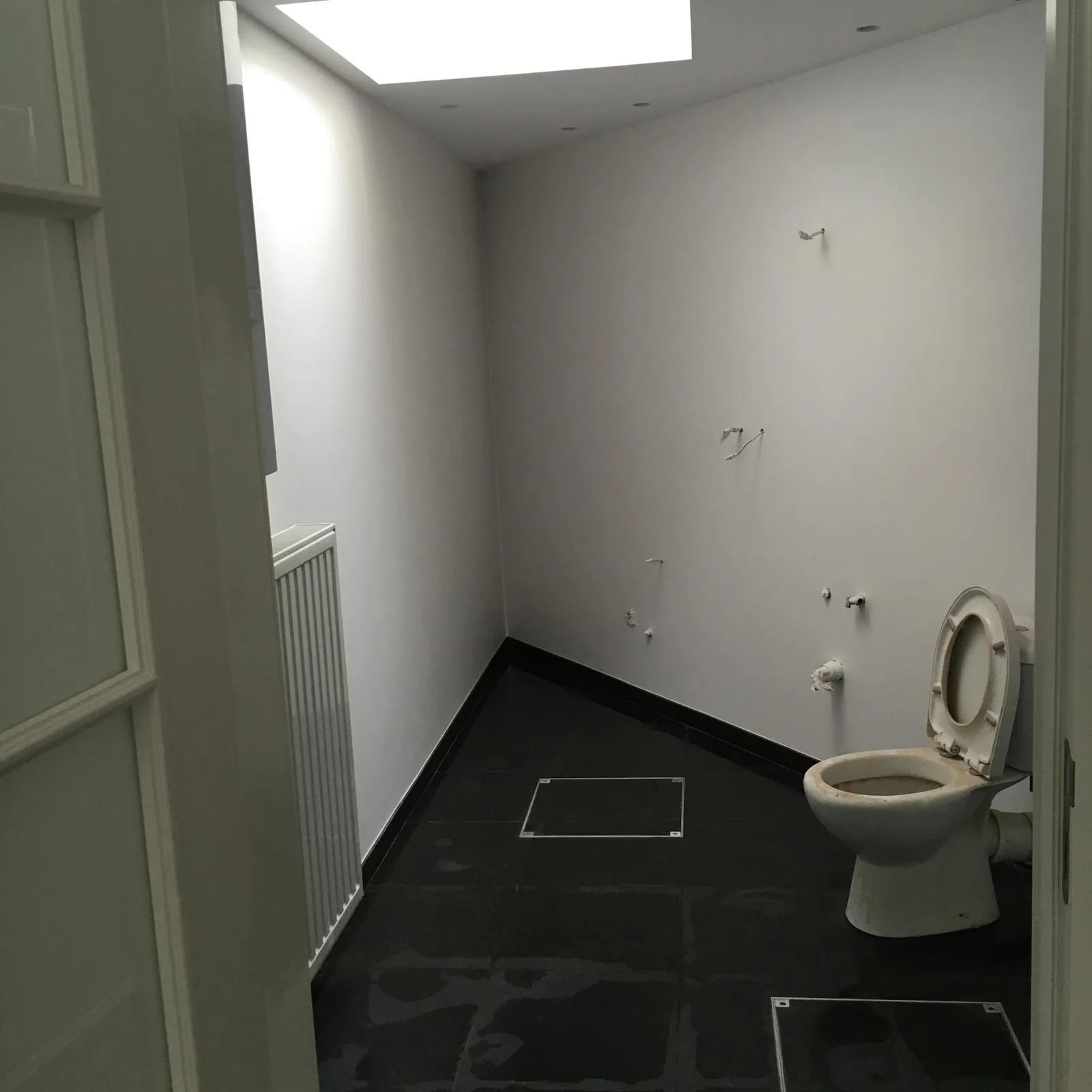 Lege badkamer met zwart tegelvloer en toilet voor renovatie