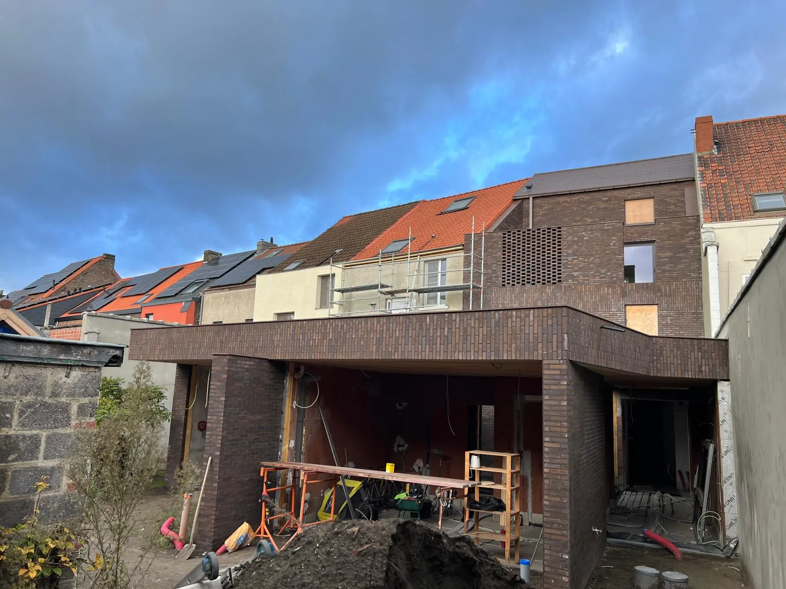 Voorzijde van een woning in aanbouw met metselwerk en bouwmateriaal