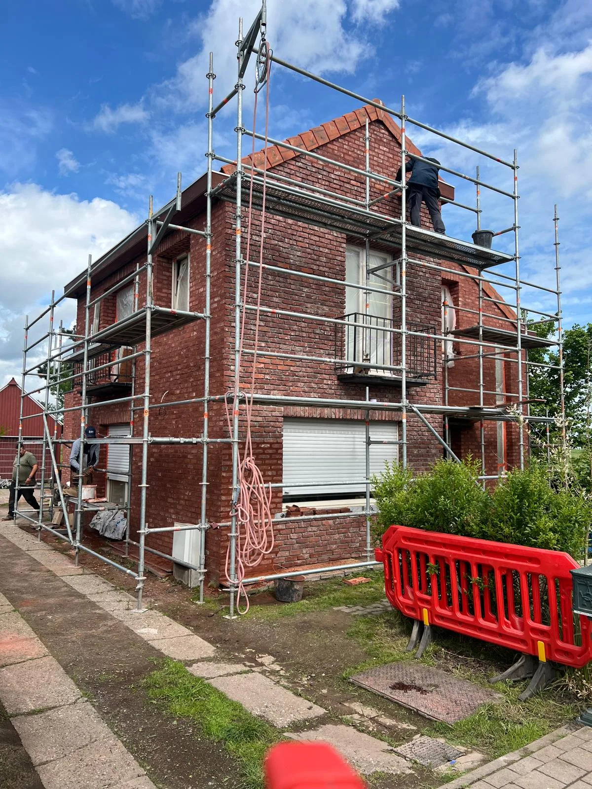 Gevelherstel en renovatie van een woning met steigers en werkers