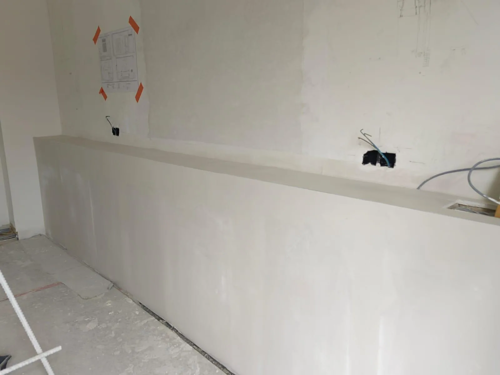 Verwerkte muur in een verbouwingsproject met gladde afwerking en aansluitingen voor elektriciteit