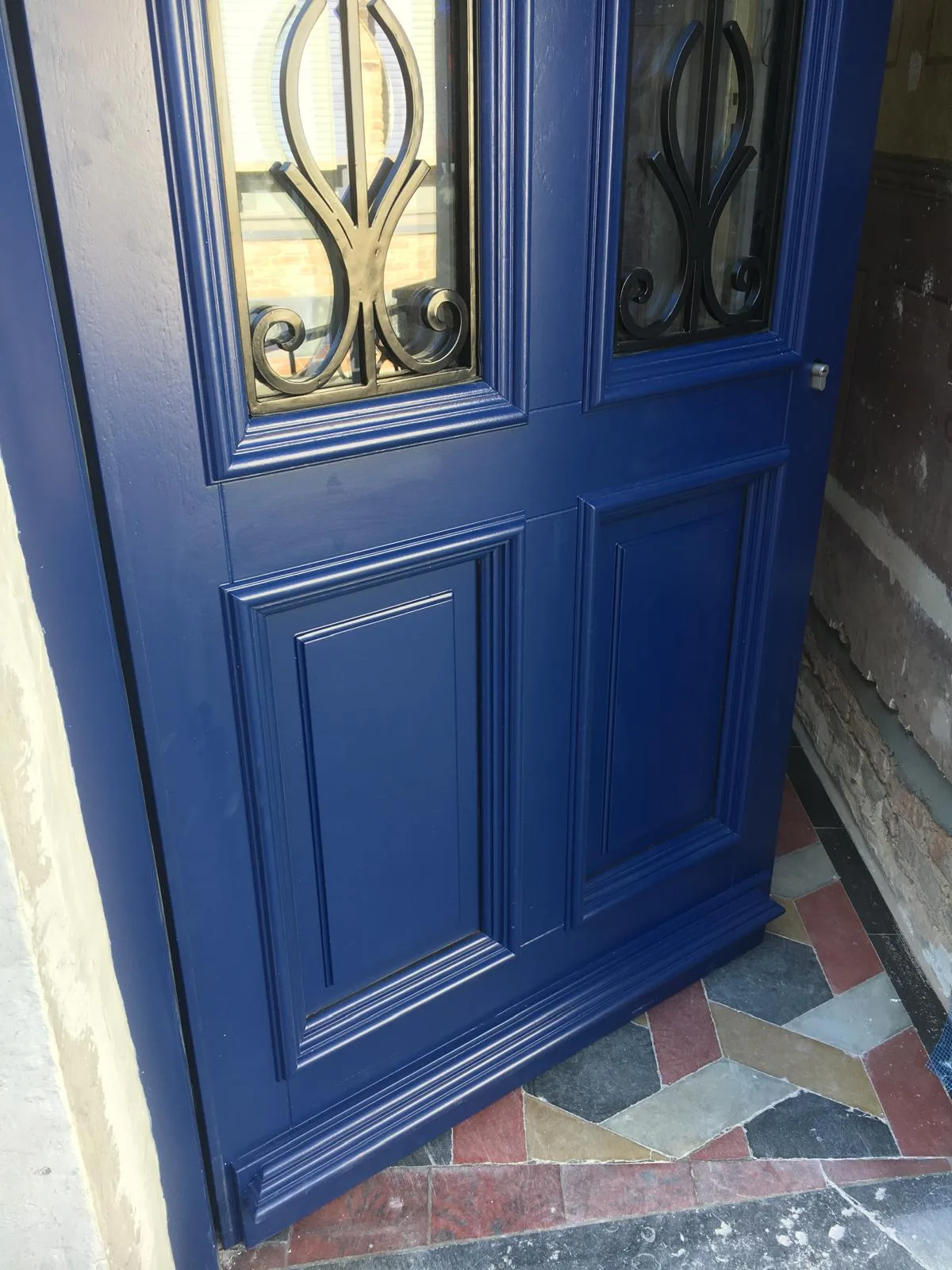 Blauw houten deur met decoratief glas en details, geplaatst in een renovatieproject