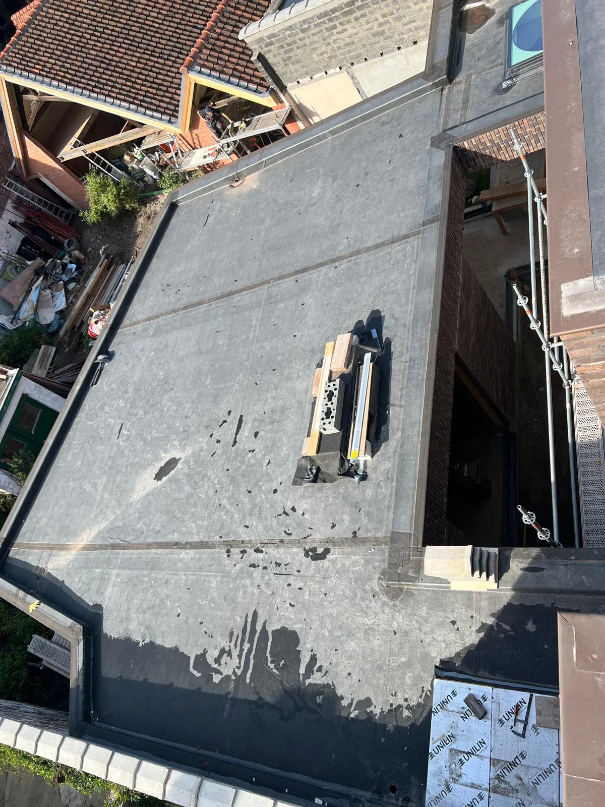 EPDM dakbedekking op een plat dak met bouwmaterialen in de omgeving