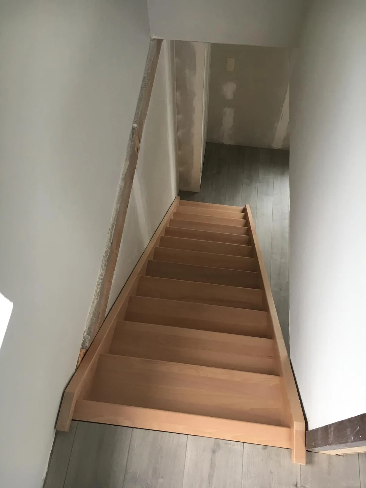 Houten trap in een woning met lichtgekleurde wanden en vloer