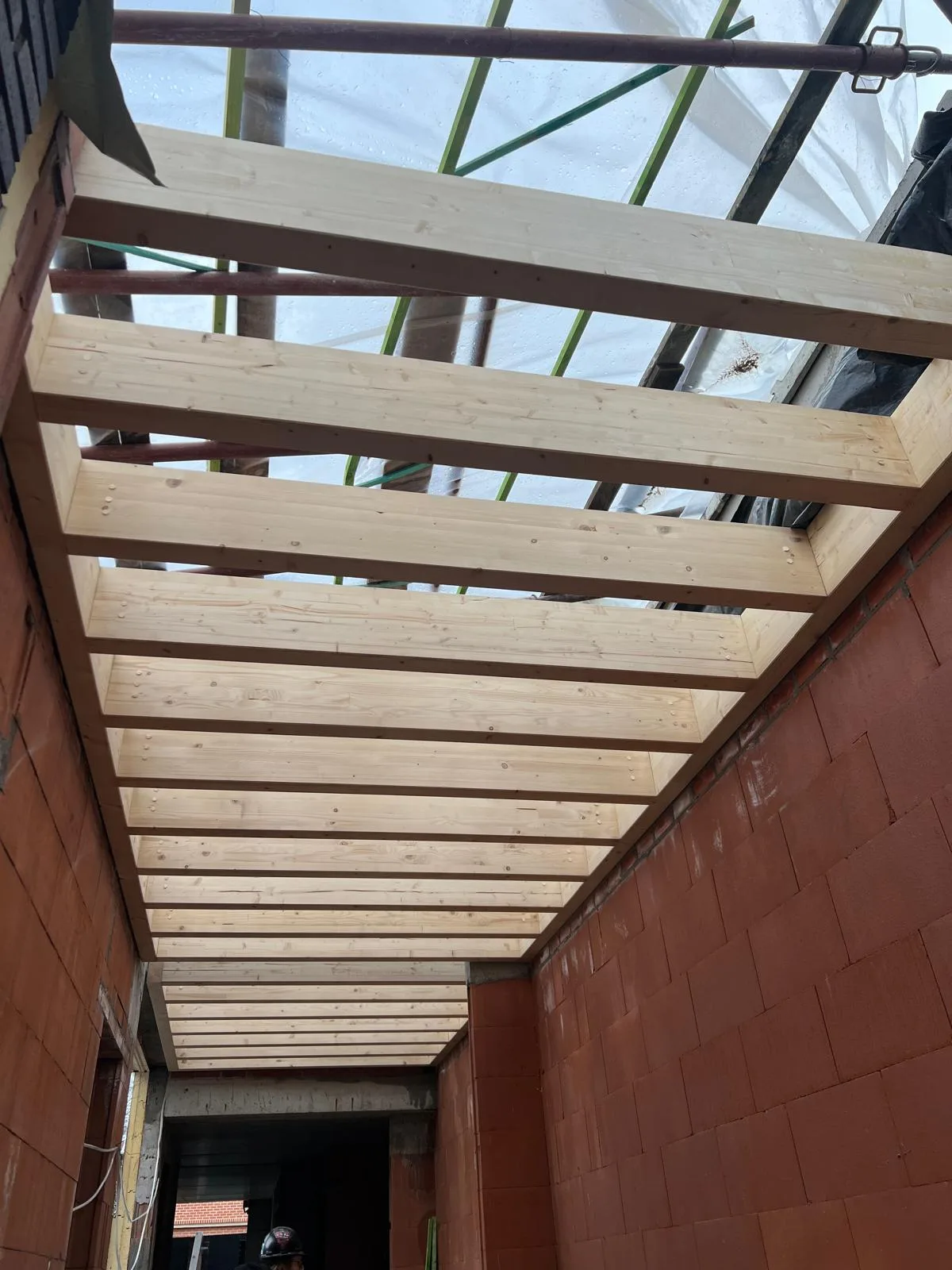 Houten constructie voor het dak met zicht op een open ruimte